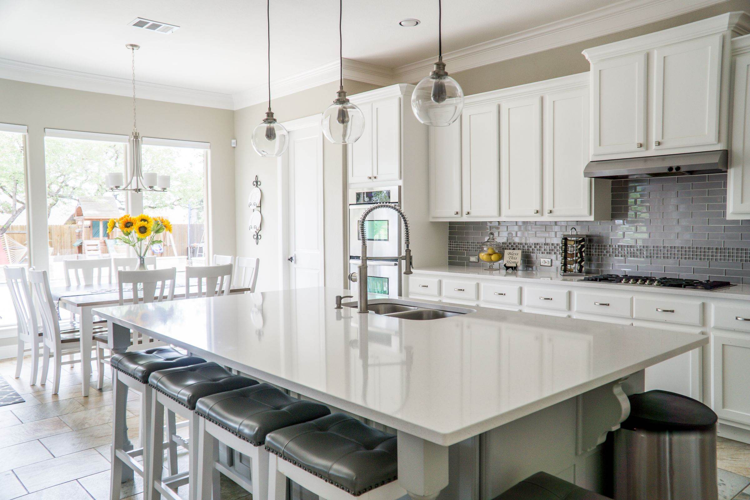 Kitchen with white painted cabinets, a large island and pendant lights