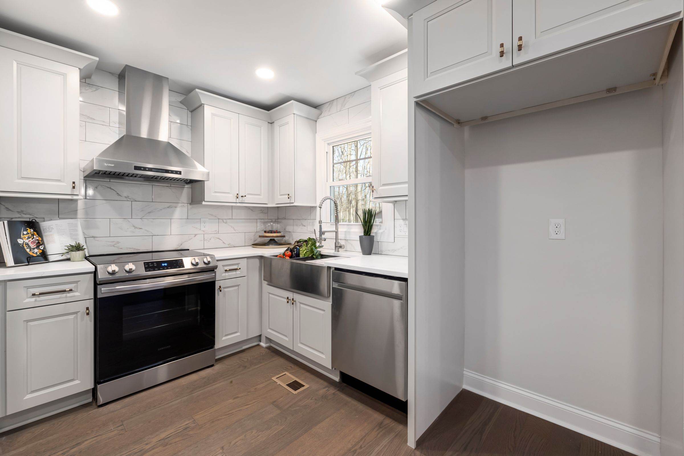 White kitchen cabinets around a range hood and stainless steel stove