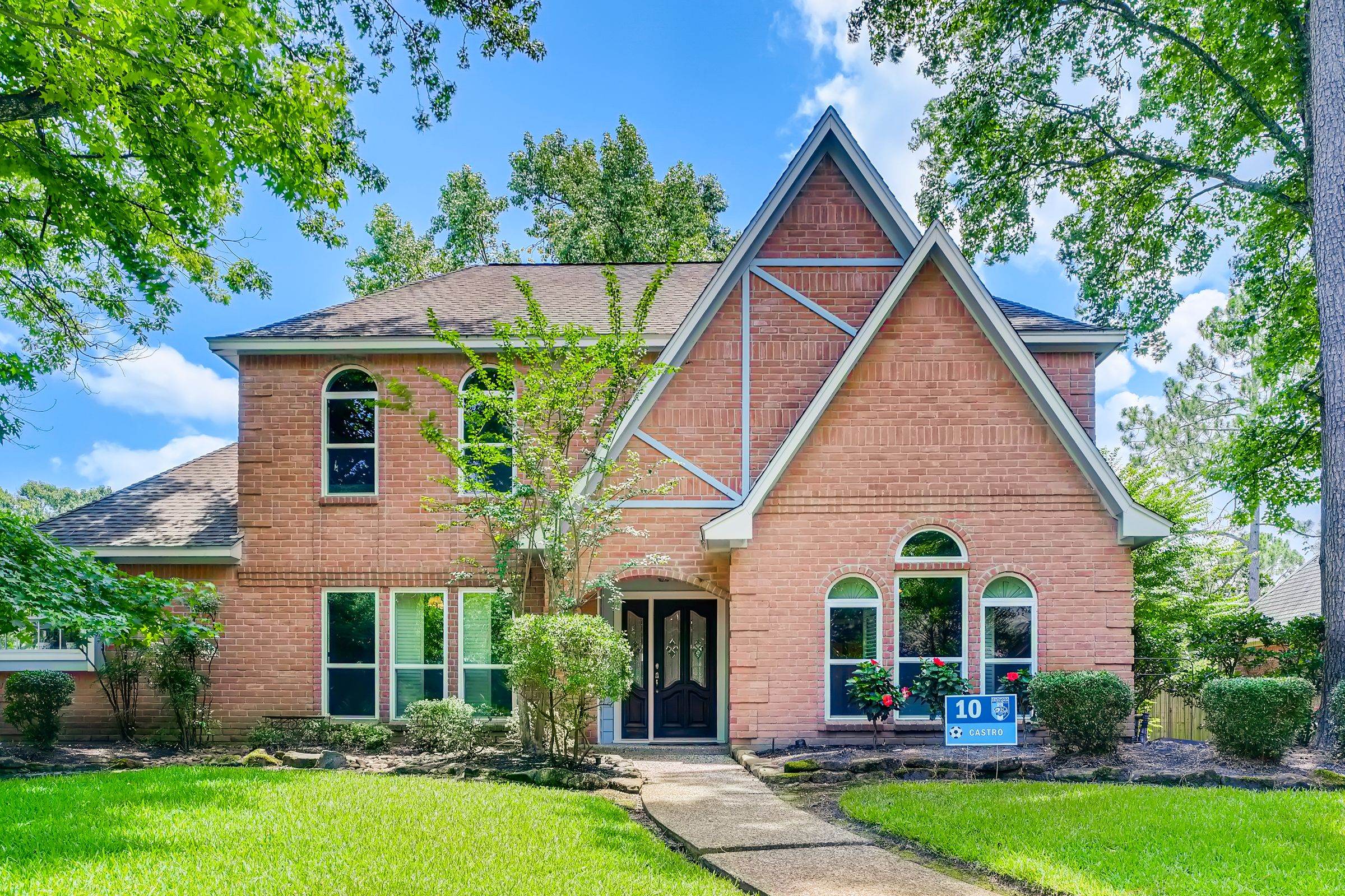 Red-brick two-story home with a steep front gable and white-painted windows