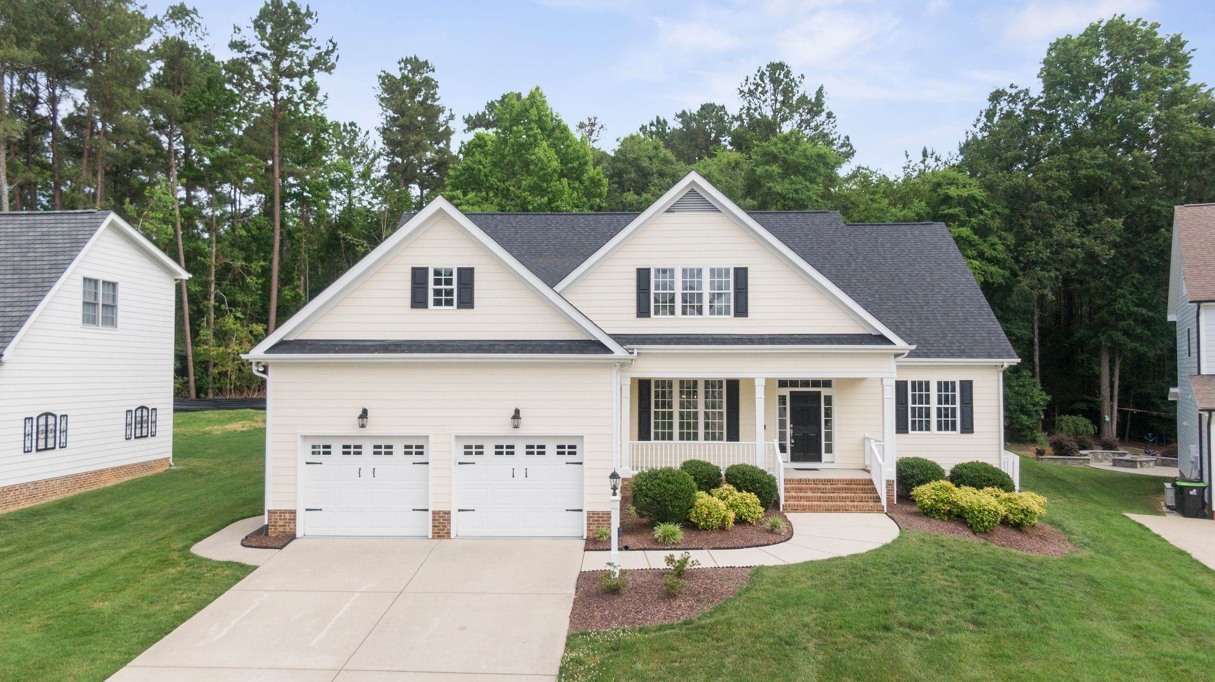 White two-story home with a covered front porch and a wide driveway