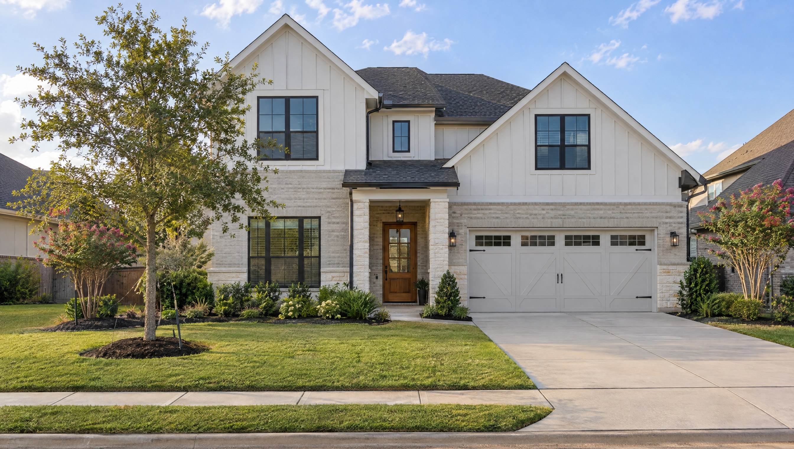 Two-story modern farmhouse-style home with white board-and-batten siding, light brick and stone, black windows and a wood front door