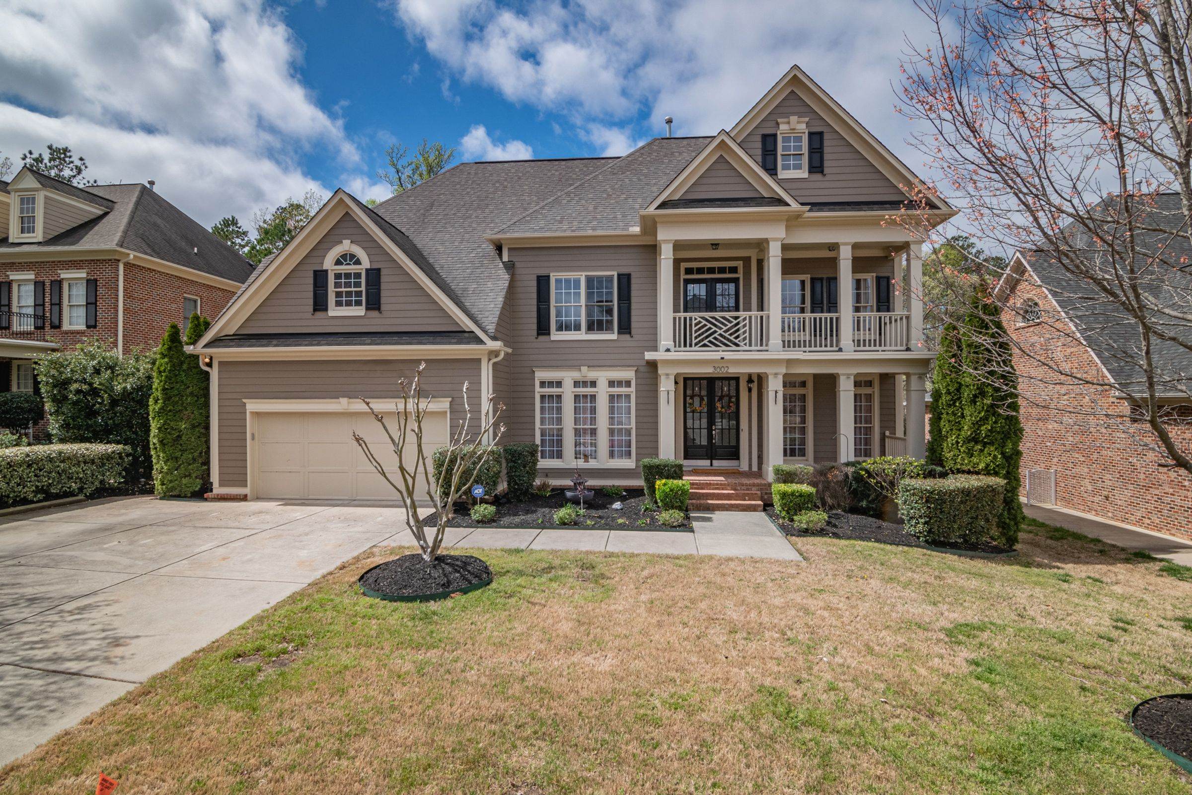 Two-story suburban home with stone and brick front, white trim and a landscaped lawn