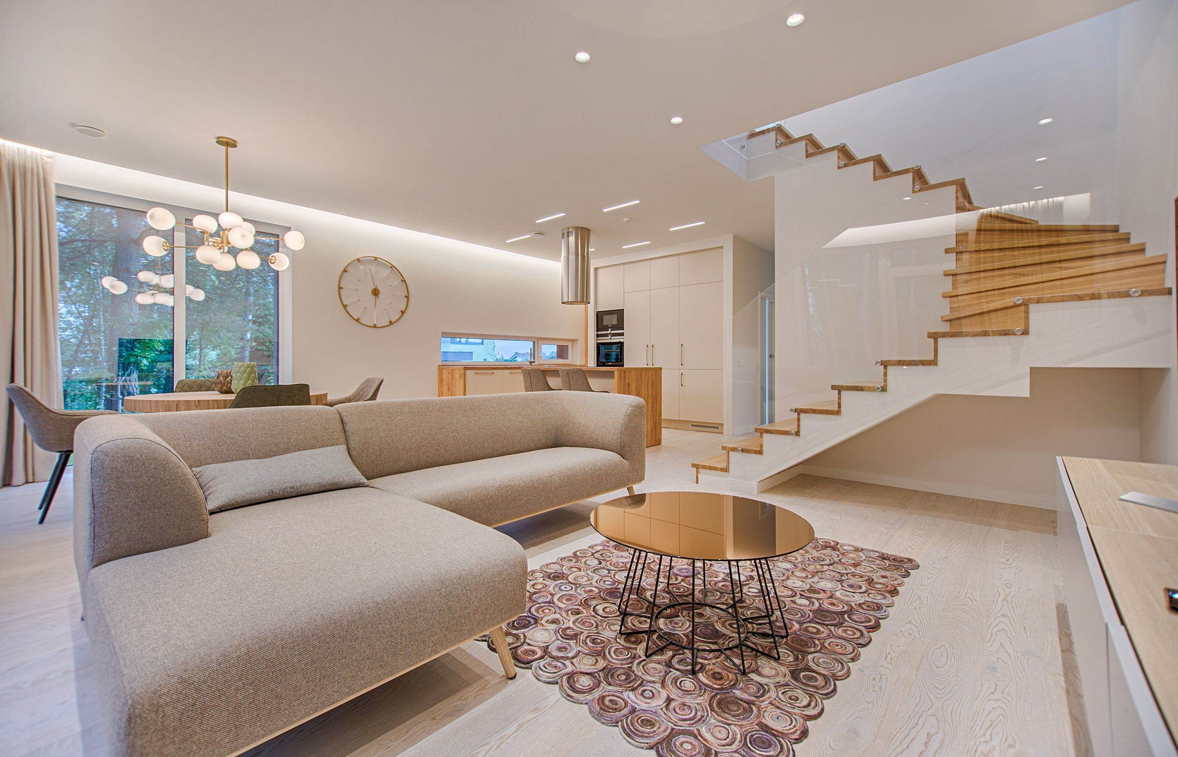 Bright living room with pale walls, a sectional sofa and an open staircase